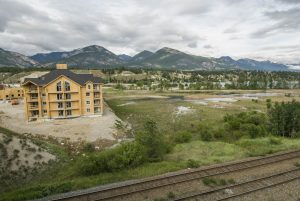 Canada:  British Columbia, Invermere, Columbia Wetlands, new development on edge of wetlands with no retaining wall, Railroad tracks at edge of Columbia Wetlands shoreline, Canadian Rocky Mountains beyond