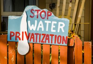 Canada:  British Columbia, Kootenay Rockies, Columbia River Basin, Kaslo on Kootenay Lake (north arm), during thunderstorm, sign for conservation on front yard fence, "Stop Water Privatization"