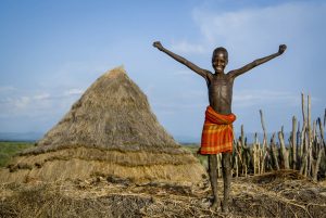 Ethiopia:  Omo River Basin, Lebuk, a Duss tribal village, Natella, young boy on top of roof