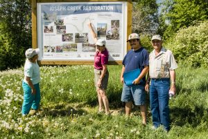Canada:  British Columbia, Cranbrook, Joseph Creek Restoration Project members in front of sign, MR