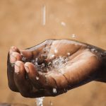 Africa:  Kenya; North Rift District, Pokot Land, Lomut, a CABESI bee collection center and eco-lodge, local child's hand collecting rainwater from gutter in thunderstorm