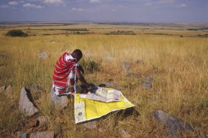 Kenya: Maasai (aka Masai) Mara National Reserve, maps of the Mara Triangle in the Mara Conservancy, being read by Maasai wilderness guide, Jackson Looseyia.
