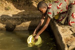 Tanzania:  No Water No Life Mara River Expedition, Mara River Basin, Tarime, girl from Angel House Orphanage collecting water from spring