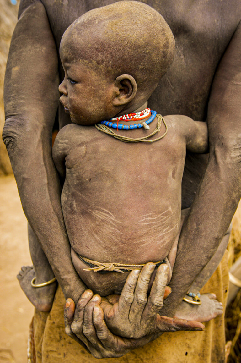 Ethiopia, Omo River Valley, a Kwego tribe's village,  mother with baby on her back