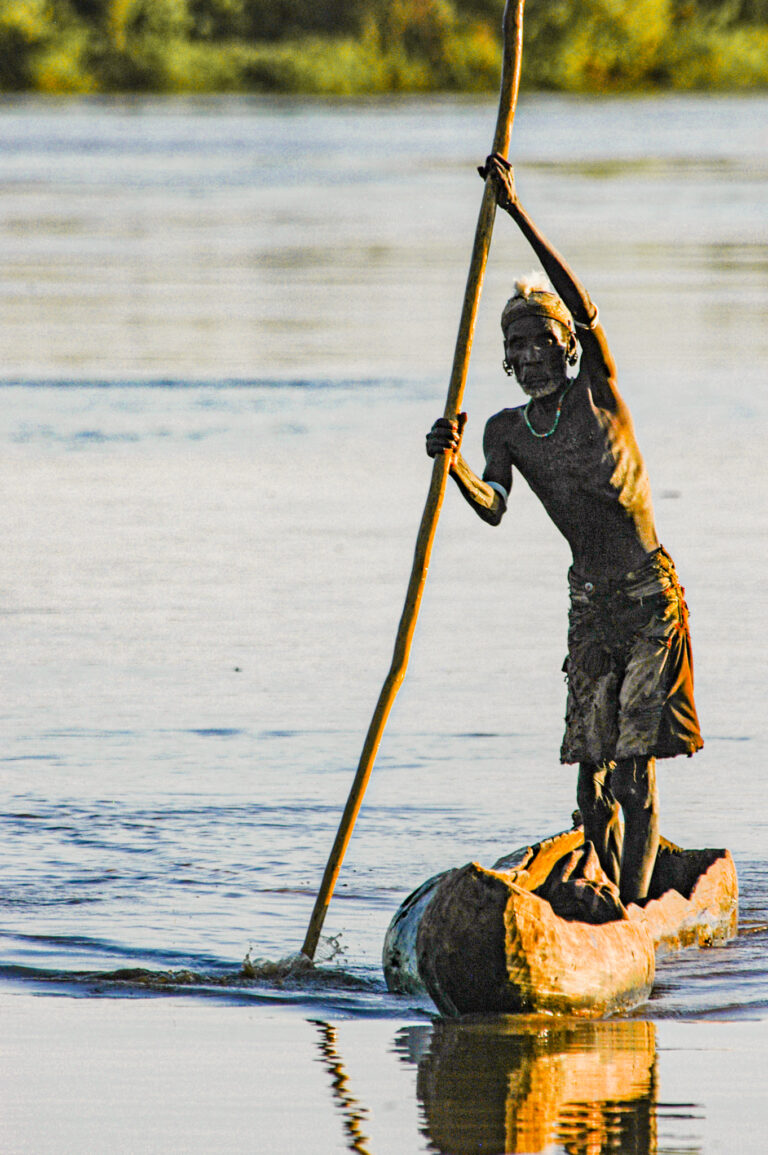 Ethiopia:  Omo River Delta, tribal territory of the Dassanech people, Dassanech plying dugout canoe across flooded OMo River